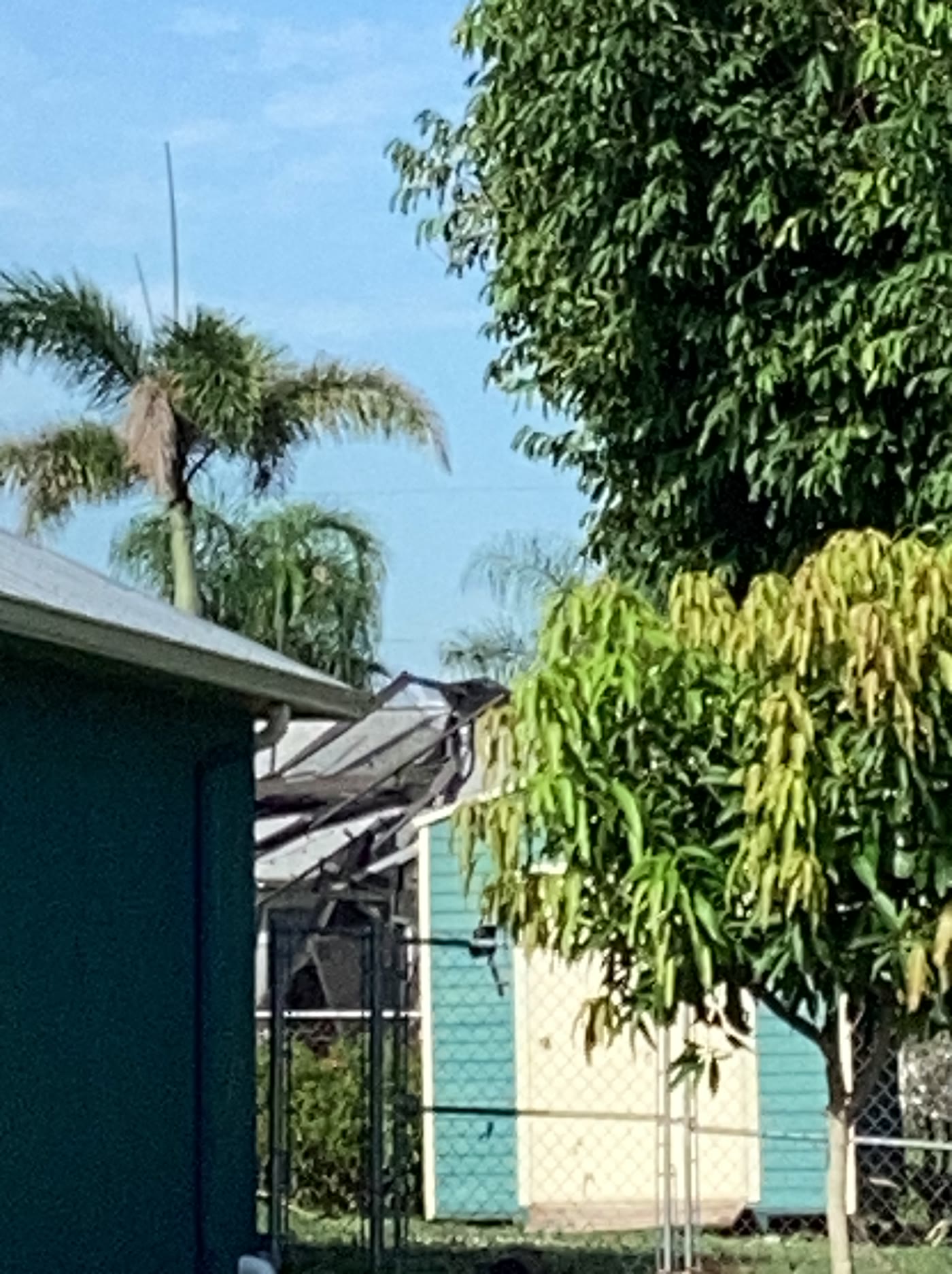 Twisted and collapsed screen-enclosure framing beside a Port St. Lucie residence after the August 23 EF-0 tornado.